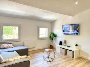 a living room with a couch and a tv on the wall at Le Jardin de la Cathédrale - T2 - Centre Ville - Emplacement & Vue Extraordinaires in Narbonne