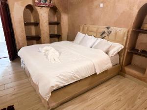 un piccolo cane bianco sdraiato su un letto di Al-Ghanima Rest House a Al Ḩamrāʼ