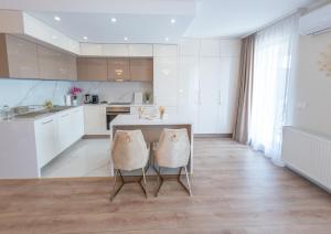 a kitchen with white cabinets and a table and chairs at Uranus Luxury Studio Apartment in Timişoara
