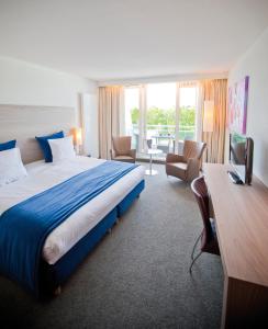 ein Hotelzimmer mit einem großen Bett und einem Schreibtisch in der Unterkunft Sanadome Hotel & Spa Nijmegen in Nijmegen