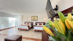 a hotel room with two beds and a flat screen tv at Hotel Quinta Tequisquiapan in Tequisquiapan