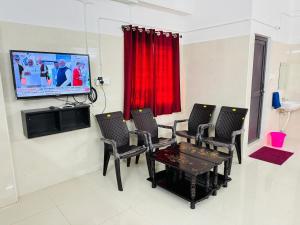 a living room with a table and chairs and a flat screen tv at MSResidency in Golden Rock