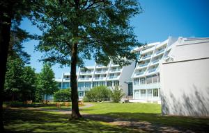 ein Baum vor einem weißen Gebäude in der Unterkunft Sanadome Hotel & Spa Nijmegen in Nijmegen