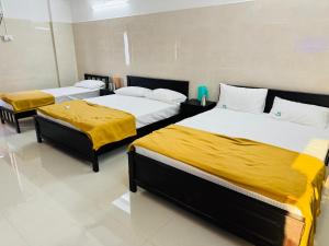 a room with three beds with yellow blankets on them at MSResidency in Golden Rock