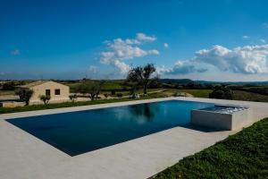 a swimming pool in the middle of a yard with a house at La Mela Di Venere in Palazzolo Acreide