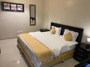 Un dormitorio con una cama grande con almohadas amarillas. en Hona Al Holm Furnished Units, en Dammam