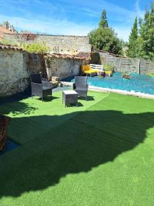 eine Terrasse mit Stühlen, einem Tisch und einem Pool in der Unterkunft Belle maison au bord du plan d'eau in Saint-Jean-dʼAngély
