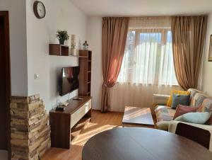 a living room with a couch and a tv at Апартаменты в Belvedere in Bansko