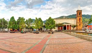 a large plaza with a building and a clock tower at Hotel el CRISTAL Muzo in Muzo