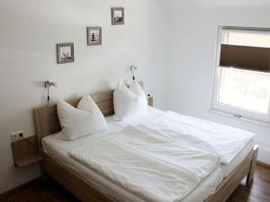 a bed with white sheets and pillows in a bedroom at Holiday apartment Villa Sonja in Zützen