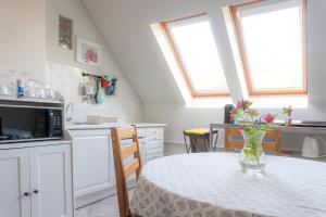 a kitchen with a table with a vase of flowers on it at Tea Apartman Balatongyörök in Balatongyörök