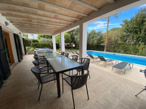 a patio with a table and chairs and a swimming pool at 5 bedroom villa with pool Puerto Pollenca Majorca in El Port