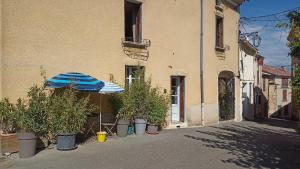 ein Gebäude mit einem Regenschirm und Topfpflanzen auf einer Straße in der Unterkunft Studio privé - maison de village in Valensole
