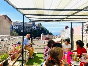 eine Gruppe von Menschen, die um einen Tisch auf einem Dach sitzen in der Unterkunft Casa Elias Hostel in Valparaíso