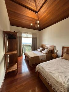 a bedroom with two beds and a large window at Casa Tramonto in Lavras Novas +6 photos
