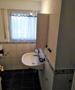 a white sink in a bathroom with a window at Ferienwohnung Volker Drews in Arnsberg