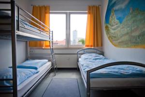 a bedroom with two bunk beds and a window at Hostel Jena in Jena
