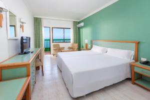 a bedroom with a large white bed and a desk at Sol Puerto de la Cruz Tenerife in Puerto de la Cruz