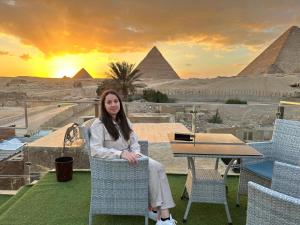 una donna seduta su una sedia di fronte alle piramidi di Golden Scarab Pyramids Hotel a Il Cairo