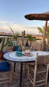 马拉喀什Riad Darnooz的露台上的一张桌子、几把椅子和一把遮阳伞