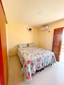 a bedroom with a bed with a floral bedspread at Nosso Chalé in Serra de São Bento