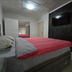 a bedroom with a large red bed with a flat screen tv at Apartment Center 23 in Podgorica