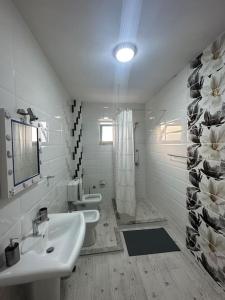 a white bathroom with two sinks and a shower at Tranquil Lakehouse in Shkodër +23 photos