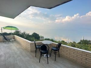 a balcony with a table and chairs and an umbrella at Tranquil Lakehouse in Shkodër
