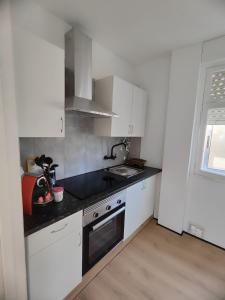 a small kitchen with white cabinets and a sink at A de Maritina - Tres Marias Apartaments in Redondela
