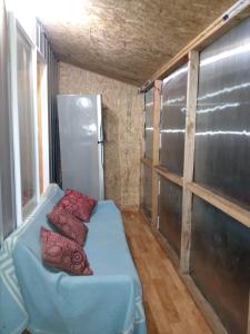 una habitación pequeña con una cama azul con almohadas rojas en cabañita Campestre, independiente, en Castro