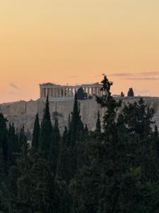 um edifício no topo de uma colina com árvores em Acropolis view em Atenas