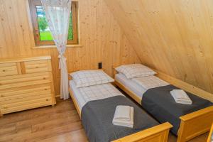 two twin beds in a wooden room with a window at Niedźwiedzia Chatka in Rzepiska