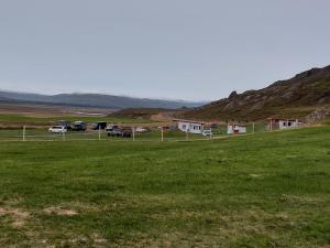 a grassy field with cars parked in a field at Ásbrandsstadir Cottages in Vopnafjörður