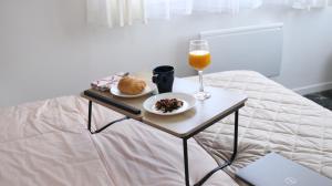 a table with a glass of orange juice and food on a bed at L'écrin de Camille et Marie in Bobigny