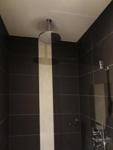y baño con ducha de azulejos negros y techo. en Sara's Boutique Hotel, en Ámsterdam