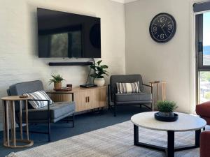 sala de estar con 2 sillas y reloj en la pared en Cobbers Rest, en Jindabyne