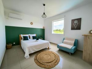 a bedroom with a bed and a chair and a window at Kukumi's House avec Piscine in Sainte-Anne +13 photos