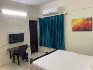 a bedroom with a bed and a desk and a television at Archrose Villa in Trivandrum