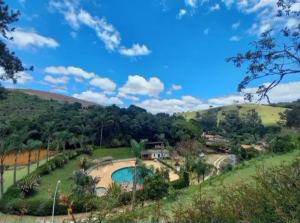 a house in a field with a swimming pool at Recanto dos Carvalhos - Pousada Camping in São Lourenço