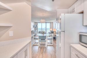 a kitchen and dining room with a white refrigerator at Ocean Trillium 803 - A 1 Bedroom Condo With Beautiful Ocean Views in New Smyrna Beach