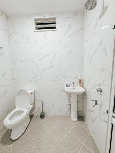a white bathroom with a toilet and a sink at Casa Kaharo 2 in Kampong Pak Sabah