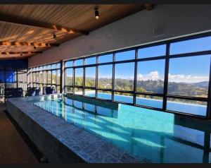 a large swimming pool in a building with windows at Room Hotel Wanderlust in Campos do Jordão
