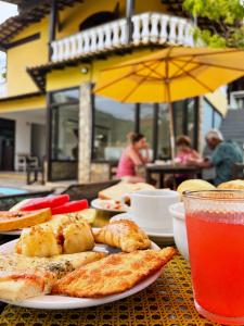a table with a plate of food and a drink at Pousada Gente Bonita João Fernandes in Búzios