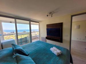 Un dormitorio con una cama grande y un televisor. en Apt Costa de Montemar, Concón, en Concón