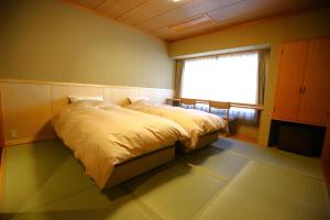 a bedroom with a large bed with a window at Nakajimaya Ryokan in Nozawa Onsen