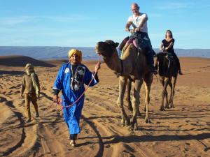 a group of people riding on camels in the desert at Atta Desert Camp in El Gouera
