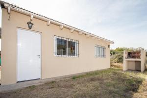 una casa blanca con una puerta blanca en Saucegrandezuna, en Balneario Sauce Grande