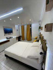 um quarto com uma grande cama branca e uma televisão em Studio spacieux en bord de mer Bas du Fort Gosier em Le Gosier