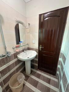 a bathroom with a sink and a wooden door at Shaiz Luxe Apartments Bhurban Murree in Murree