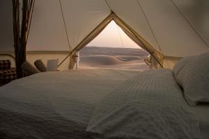 BadīyahThe One - Sunset private Tent camp的沙漠帐篷内的一张床位